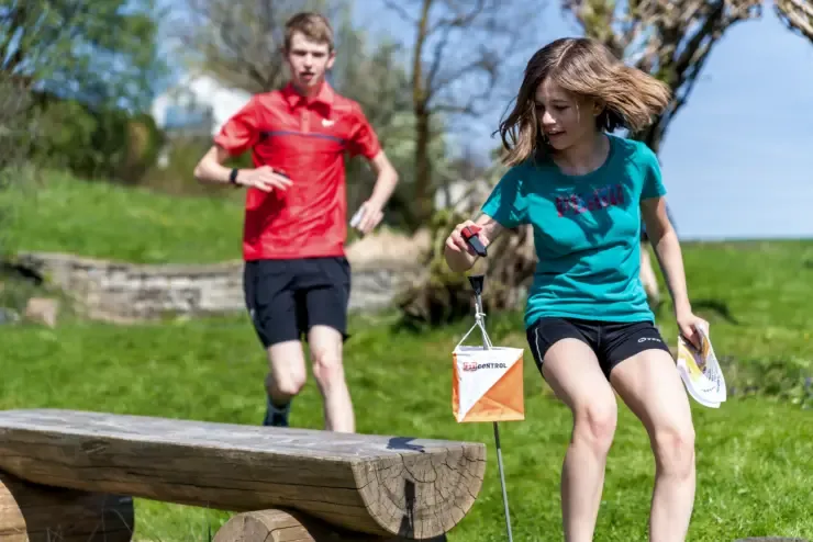 Jugendliche beim Orientierungslauf: Ein Mädchen quittiert mit dem FixLogger einen Posten, ein Knabe läuft hinterher.